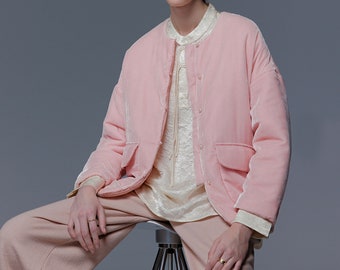 Puede incluir: Una chaqueta de terciopelo rosa con cierre de botón de perla y dos bolsillos de parche. La chaqueta tiene un corte holgado y está forrada con un tejido blanco.