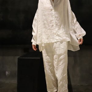 Pu&ograve; includere: Un set di camicia e pantaloni in lino bianco. La camicia ha una vestibilit&agrave; rilassata e una chiusura con bottoni sul davanti. I pantaloni sono corti e hanno una gamba larga.