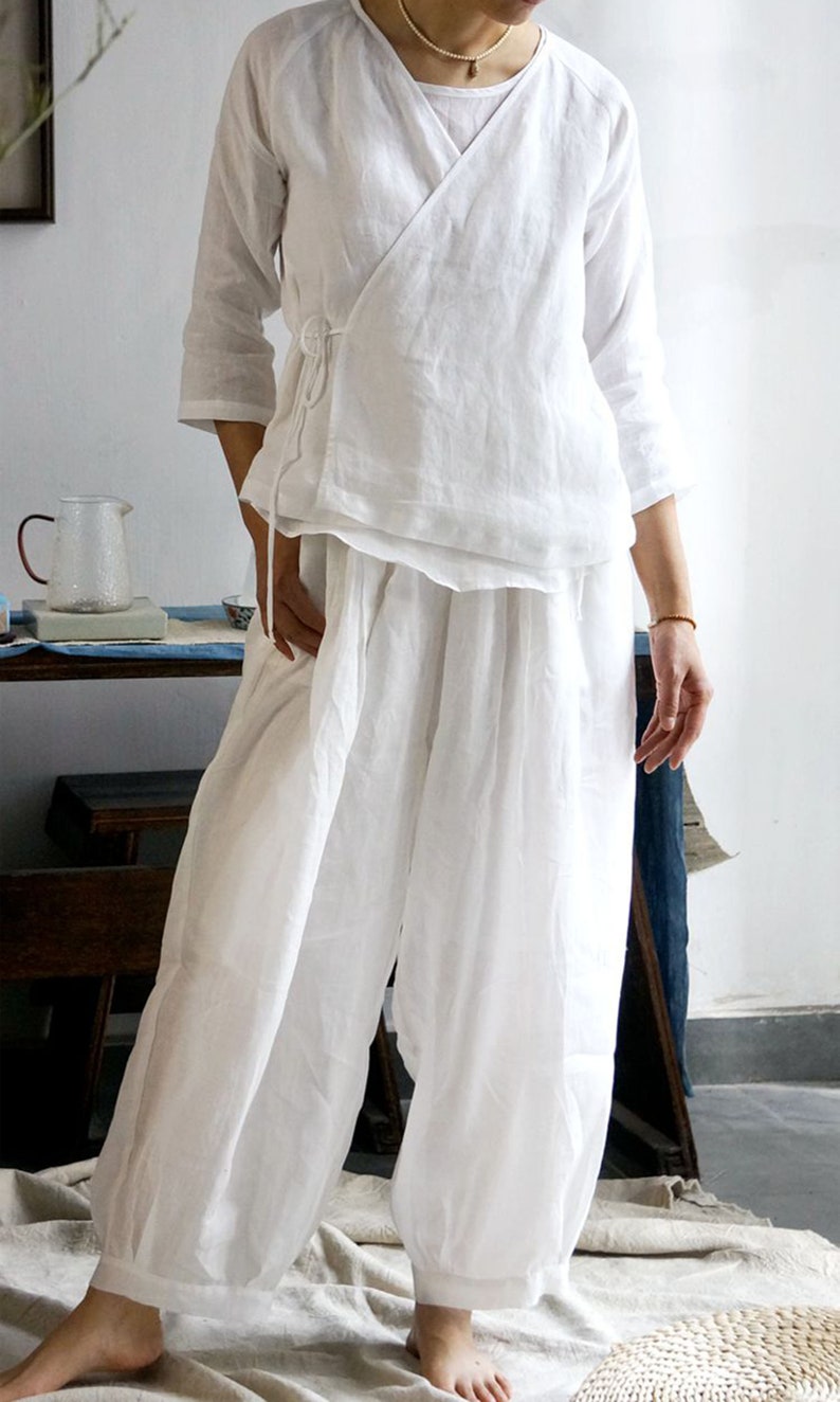 May include: A white linen wrap top with a long tie and matching wide-leg pants. The top has a V-neck and three-quarter sleeves.