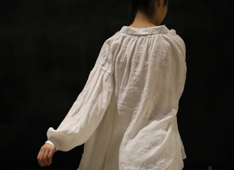 Pu&ograve; includere: Una camicia bianca larga con scollo arricciato e maniche lunghe. La camicia &egrave; realizzata in un tessuto leggero e ha un aspetto rilassato e casual.