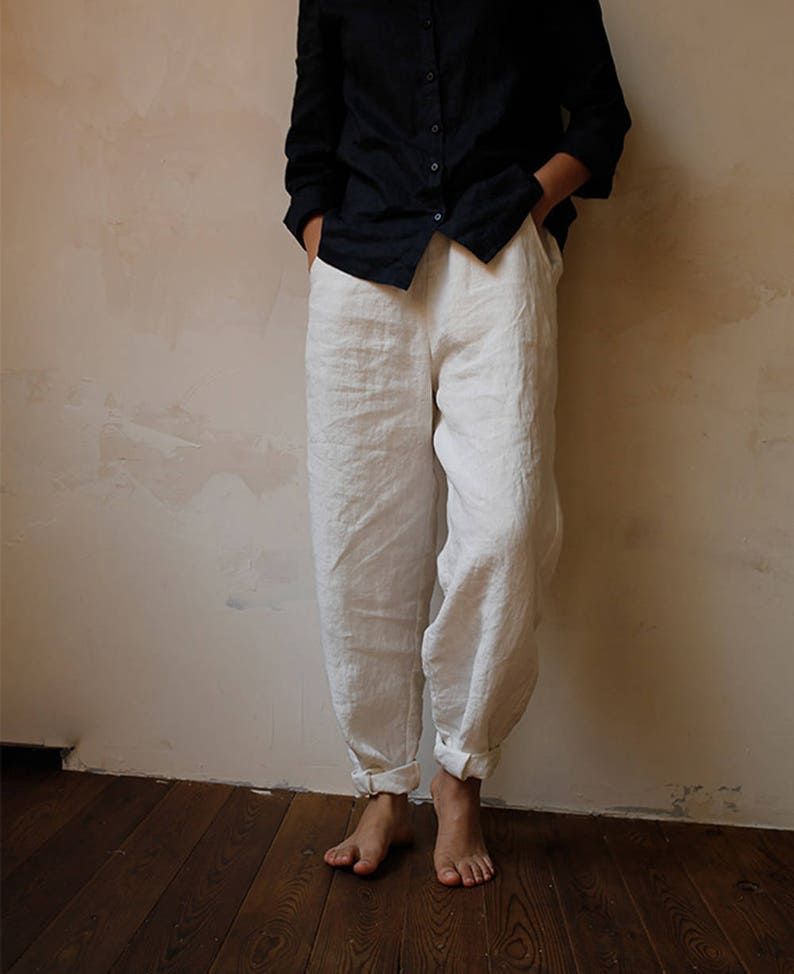 May include: White linen trousers with a relaxed fit and cuffed hems. The trousers are made from a lightweight fabric and have a casual style.
