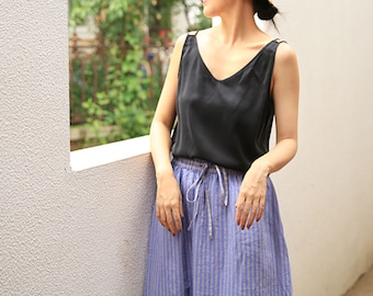 May include: A black V-neck tank top and blue striped skirt. The tank top has thin straps and a flowing silhouette. The skirt is a light blue with vertical white stripes and a drawstring waist. The outfit is casual and suitable for warm weather.