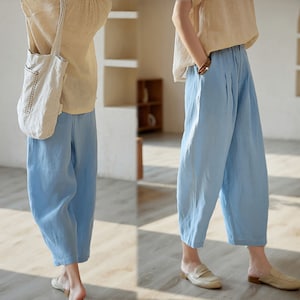 May include: A pair of light blue linen pants with a wide leg and a relaxed fit. The pants are shown on a model wearing a beige top.