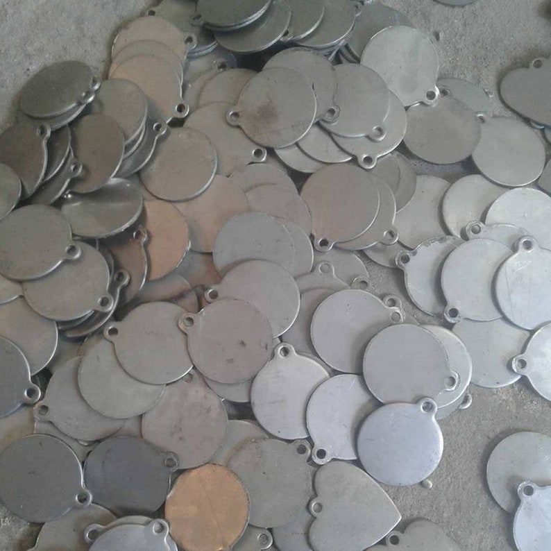 May include: A pile of round, silver metal targets with a hole in the center. The targets are stacked on top of each other and are all the same size.