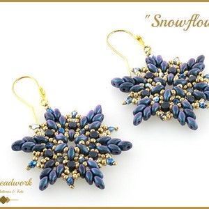 Op de afbeelding: Een paar gouden sneeuwvlok oorbellen met blauwe en gouden kralen. De oorbellen worden "Snowflowers" genoemd.