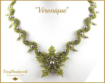 May include: A green and silver beaded necklace with a snowflake pendant. The necklace is called "Véronique".