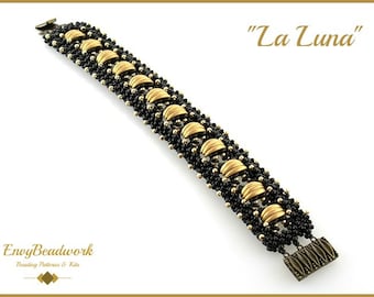 May include: A beaded bracelet with the text "La Luna". The bracelet features black beads and gold-colored, half-moon shaped accents. The clasp is a dark bronze color. The bracelet is a jewelry item.