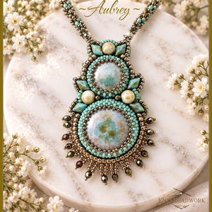 May include: A beaded pendant necklace titled Aubrey, featuring two large circular turquoise and brown cabochons surrounded by small turquoise and metallic bronze seed beads, accented with cream-colored beads and a fringe of bronze crystals.