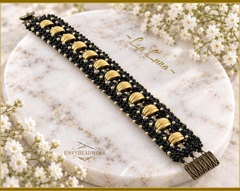 May include: A beaded bracelet featuring a central row of curved, matte gold-toned metal segments flanked by rows of small, black seed beads and tiny gold-toned accent beads. The bracelet includes a rectangular, antique gold-toned metal clasp.