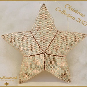 Op de afbeelding: Een witte en koperen parelster met een lus om op te hangen. De ster is gemaakt van kleine kralen en heeft een geometrisch patroon. De ornament is onderdeel van een kerstcollectie.