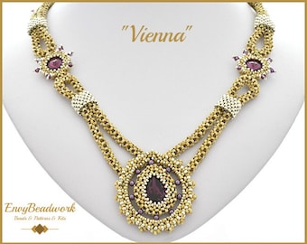 May include: A gold and silver beaded necklace with a large purple gemstone pendant. The necklace has a repeating pattern of small beads and larger beads. The pendant is surrounded by a circle of smaller beads. The necklace is labeled "Vienna".