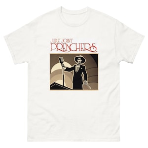 May include: White t-shirt with a black and white illustration of a skeleton in a suit holding a microphone. The text "JUKE JOINT PREACHERS" is printed in red above the illustration.
