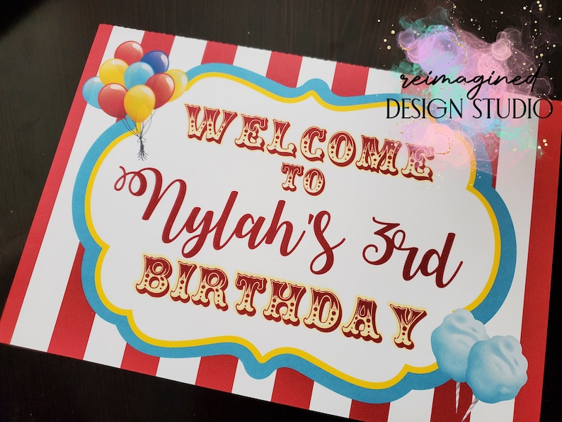 Peut inclure: Panneau d'accueil pour le 3&egrave;me anniversaire de Nylah avec un fond ray&eacute; rouge et blanc, une bordure bleue et jaune et un th&egrave;me de cirque. Le panneau pr&eacute;sente une banni&egrave;re de bienvenue, des ballons et de la barbe &agrave; papa.