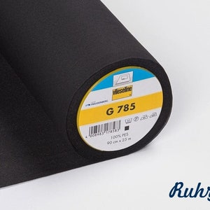 Pode incluir: Um rolo de tecido de entretela preto com a etiqueta "Vlieseline G 785" com instruções de cuidados e dimensões: 100% PES, 90 cm x 25 m.