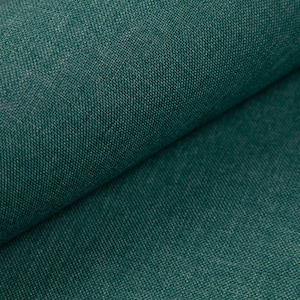 Könnte beinhalten: Nahaufnahme eines gefalteten, teal-farbenen Stoffes. Der Stoff hat eine strukturierte Optik mit einem subtilen, verwobenen Muster. Die Farbe ist ein tiefes, sattes Teal, mit helleren Highlights, die Tiefe erzeugen.
