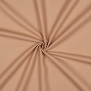 Può includere: Primo piano di un tessuto beige con un motivo a spirale al centro. Il tessuto è morbido e sembra essere di colore uniforme. Le pieghe del tessuto creano un effetto vorticoso.