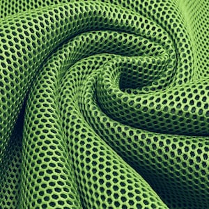 Op de afbeelding: Groen mesh-stof met een textuur, honingraatpatroon. De stof is gevouwen en gedrapeerd, waardoor een zachte, vloeiende look ontstaat.