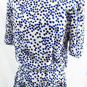 May include: A white dress with a blue and black polka dot pattern. The dress has a short sleeve and a fitted bodice. The skirt is gathered at the waist.