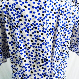 May include: A white dress with a blue and black polka dot pattern. The dress has a button closure down the back.