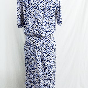May include: A white dress with a blue and black polka dot pattern. The dress has short sleeves and a fitted bodice. The skirt is gathered at the waist and falls to the knees.