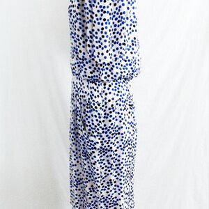 May include: A white dress with a blue and black polka dot pattern. The dress is on a mannequin and has a fitted bodice and a skirt that falls to the knees.