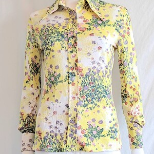 May include: A yellow long-sleeved button-up shirt with a floral print in shades of pink, purple, and green.