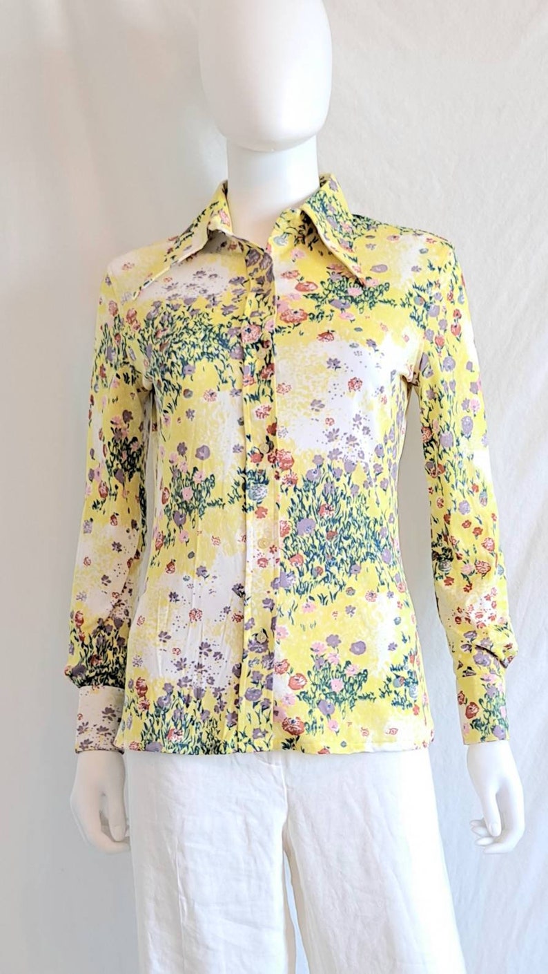 May include: A yellow long-sleeved button-up shirt with a floral print in shades of pink, purple, and green.