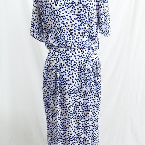 May include: A white dress with a blue and black polka dot pattern. The dress has a short sleeve and a fitted bodice. The skirt is slightly flared and falls to the knee.