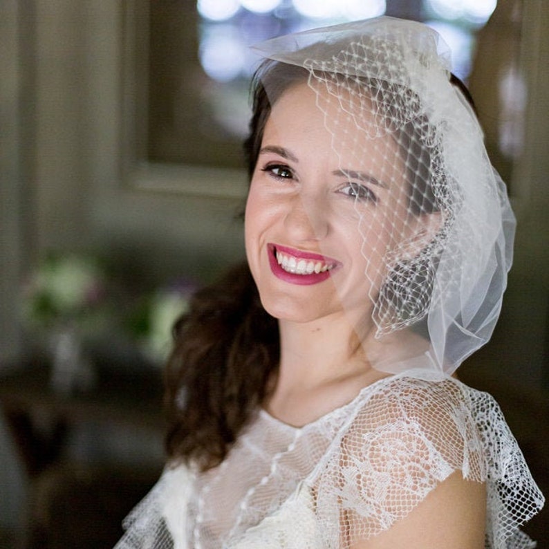 May include: A bride wearing a white lace dress with a white veil. She is smiling and looking to the side.