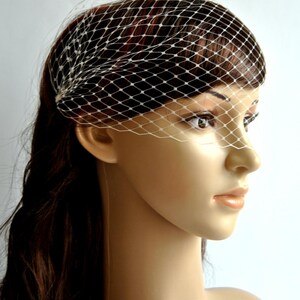 May include: A white bridal veil with a delicate net pattern. The veil is worn on a mannequin with long brown hair.