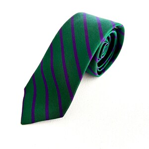 May include: A green and purple striped tie. The tie is rolled up and ready to be worn.