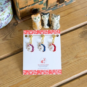 May include: Three gold unicorn stitch markers with purple, blue, and red enamel accents. The markers are displayed on a white card with the text "the crimson rabbit" and a website address.