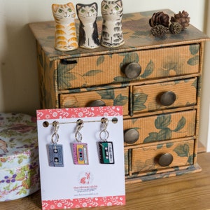 May include: Three colourful cassette tape stitch markers with silver rings. The markers are displayed on a white card with the text "the crimson rabbit" and a website address.