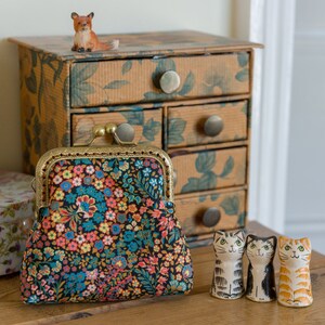 Monedero hecho con Liberty Tana Lawn con el estampado: 'Little Marquess', un forro de bronce y oro y una estructura de metal de bronce cosida a mano.