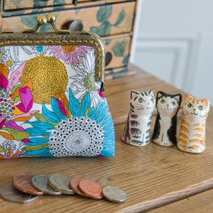 Monedero elaborado con Liberty Tana Lawn con estampado Susannah, un forro dorado y un marco de metal color bronce cosido a mano.