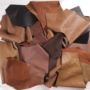 May include: A collection of assorted leather scraps in various shades of brown, tan, and black. The pieces feature smooth and textured surfaces with irregular shapes and edges, showcasing different thicknesses and natural grain patterns throughout.