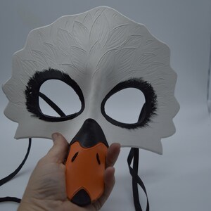 Op de afbeelding: Witte zwanenmasker met zwarte ooggaten en een oranje snavel. Het masker heeft een zwart elastisch bandje.