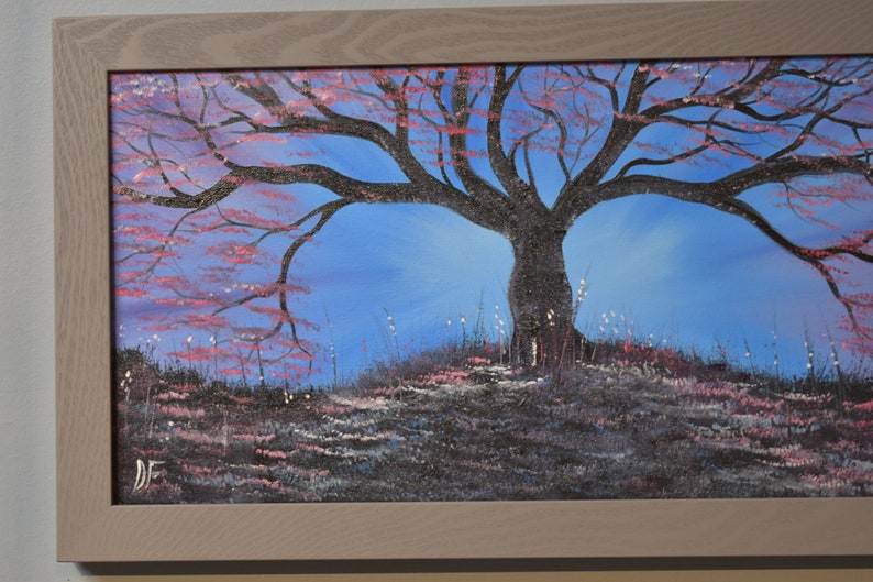 K&ouml;nnte beinhalten: Ein Gem&auml;lde, das einen silhouettenartigen Baum mit rosa Bl&uuml;ten vor einem blauen Himmel zeigt. Der Baum befindet sich in der Mitte des Gem&auml;ldes und ist von einem Grasfeld umgeben. Das Gem&auml;lde ist in einem hellen Holzrahmen gerahmt.