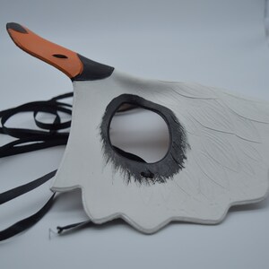 Op de afbeelding: Witte zwanenmasker met zwarte ooggaten en een oranje snavel. Het masker heeft een zwart lint om vast te binden.