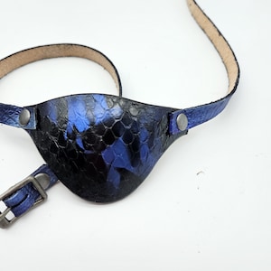 May include: A blue leather eye patch with a snakeskin pattern and a silver buckle.