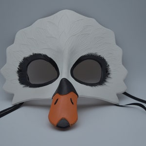 Op de afbeelding: Witte zwanenmasker met zwarte ooggaten en een oranje snavel. Het masker heeft zwarte banden.