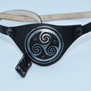 May include: Black leather eye patch with an adjustable strap and a silver Celtic knot design.