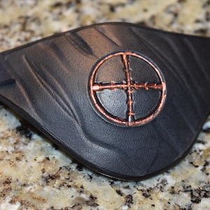 May include: Black leather eye patch with a copper-colored target design.
