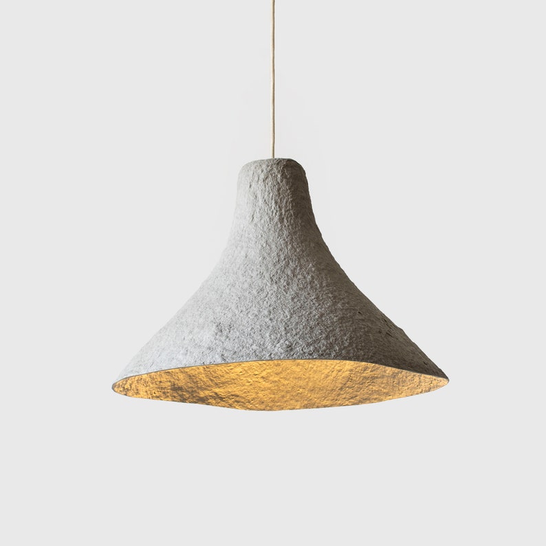 May include: A white, textured, paper pendant light fixture with a wide, bell-shaped shade.