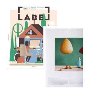 K&ouml;nnte beinhalten: Ein Magazincover mit einer Illustration eines Hauses mit einer Person, die an einem Schreibtisch arbeitet. Das Magazin hei&szlig;t "LABEL" und die Nummer des Heftes ist 27. Das Magazin liegt neben einer Seite aus einem anderen Magazin mit einem Foto einer Leuchte, die &uuml;ber einem Tisch mit gr&uuml;nem Hintergrund h&auml;ngt.