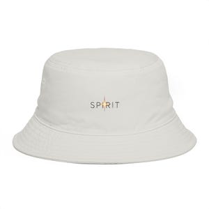 Peut inclure: Un bob blanc avec le mot SPIRIT imprimé en lettres noires sur le devant. La lettre I est remplacée par un graphique d'étoile stylisée avec des rayons lumineux orange et jaunes émanant du centre, créant un point focal brillant.