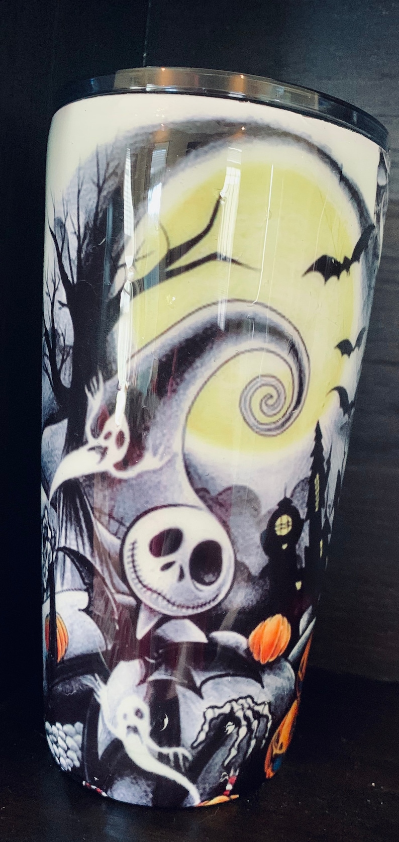 K&ouml;nnte beinhalten: Ein wei&szlig;er Becher mit einem Schwarzwei&szlig;bild von Jack Skellington aus Nightmare Before Christmas. Das Bild zeigt au&szlig;erdem einen Vollmond, Flederm&auml;use und ein Spukhaus.