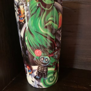 K&ouml;nnte beinhalten: Ein gr&uuml;ner und schwarzer Edelstahlbecher mit einem grafischen Aufdruck von Figuren aus Nightmare Before Christmas. Die Figuren sind Jack Skellington, Sally und Oogie Boogie.