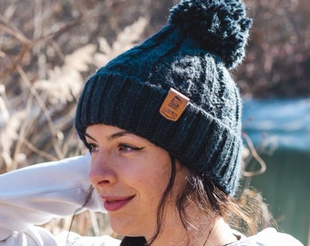 May include: A dark blue knit beanie with a pom pom on top. The beanie has a brown leather patch with the text "Urban Box" on it.