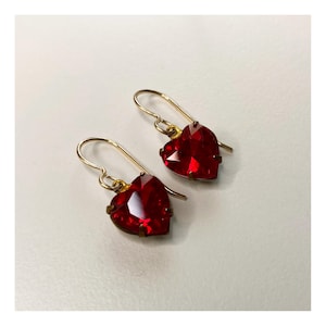May include: A pair of gold heart-shaped earrings with red gemstone accents.